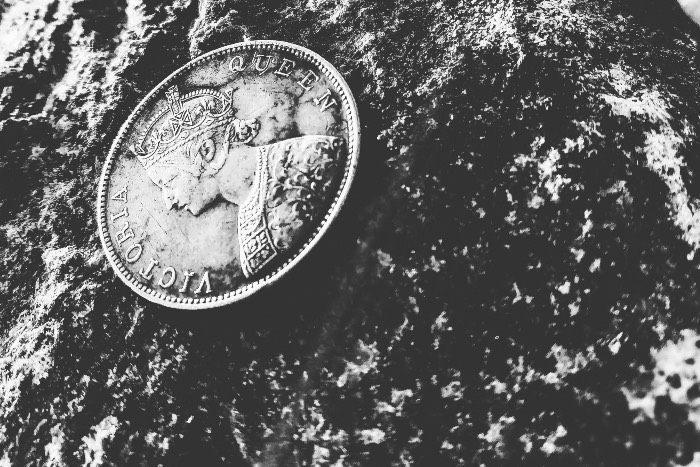 a black and white photo of a coin on a rock—the inscription says Queen Victoria