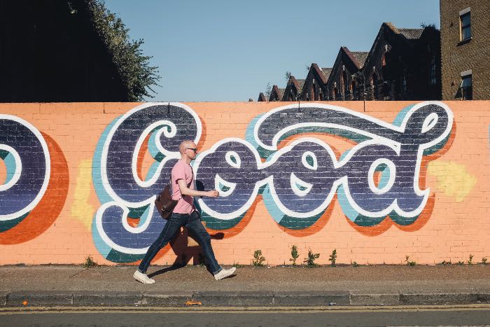 "Feeling Justified" - a photo of a person walking in front of a wall with the word "good" on it.