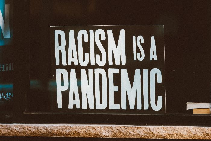"Open season for racists after Musk's takeover" - a photo of a sign that reads "Racism is a pandemic"