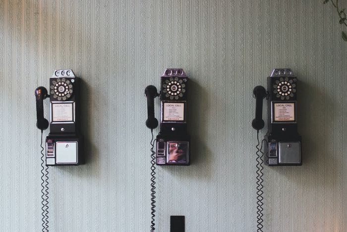 "Writing about communication" - a photo of three old, coin-operated rotary telephones on a wall