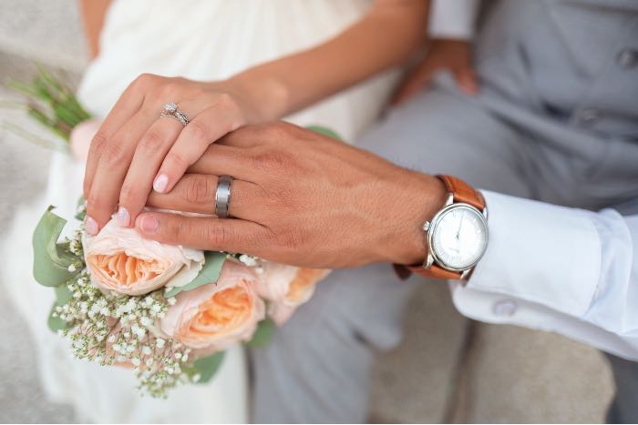"So many husbands" - a photo of the hands of a newly-married couple, placed so we can see their rings.