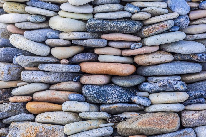 "Testify—having the words to say" - a closeup photo of many thin rocks stacked like a wall made of skipping stones.