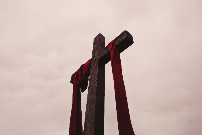 "They don't know" - a photo of a cross draped with red cloth.