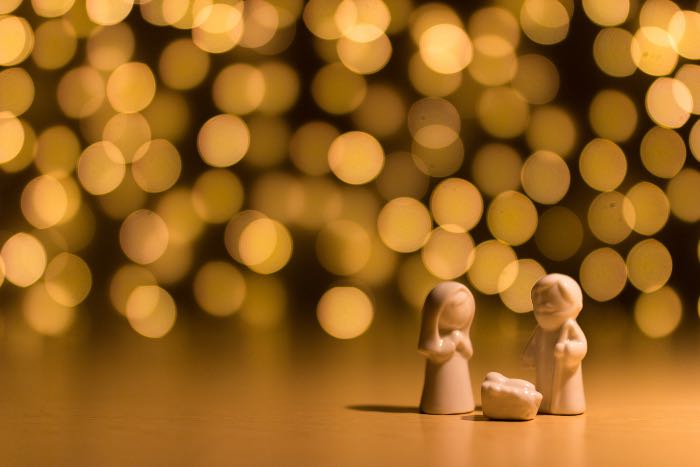 "All About Joseph?" - a photo focused on wooden figures of the Holy Family, while the background and lights are out of focus.