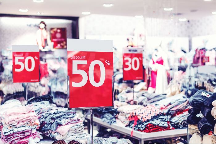 "Buying Stuff" - a photo inside a clothing store with signs declaring 50% off.