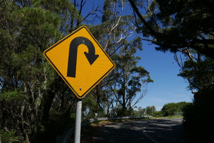 "Becoming Prophetic" - a photo of a sign depicting a U-turn.