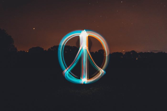 "Peacemaker" - a photo of a dark scene in the background and in the foreground, a peace sign made of light.