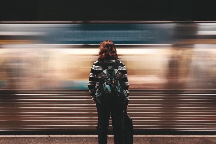 "Active Participation" - a photo of a person waiting for the subway train to stop as it rushes by.