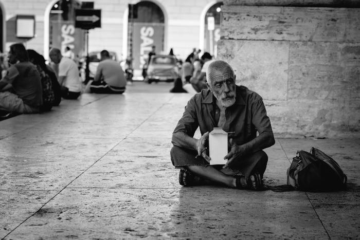 "The Beatitudes" - a photo of a person sitting on the sidewalk.