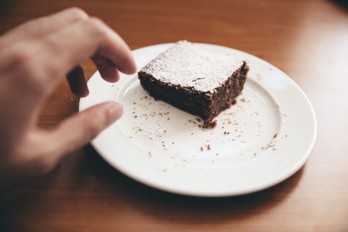 "Temptation" - a photo of a hand reaching for a brownie on a plate.