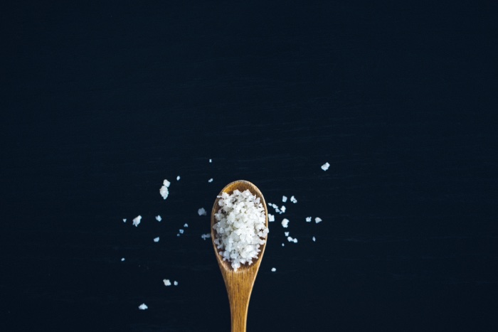 "salty" - a photo of a wooden spoon full of rock salt