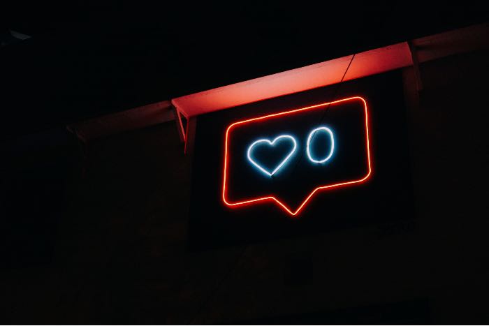"social media" - a photo of a neon sign shaped to look a social media "love" symbol with a count of zero.