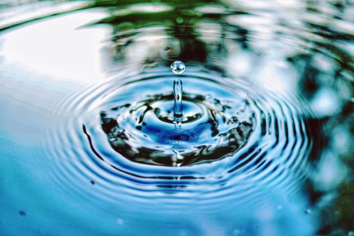 a photo of a drop, wrippling the surface of the water
