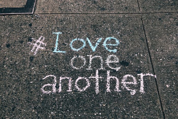 a photo of a sidewalk with "# Love one another" in chalk