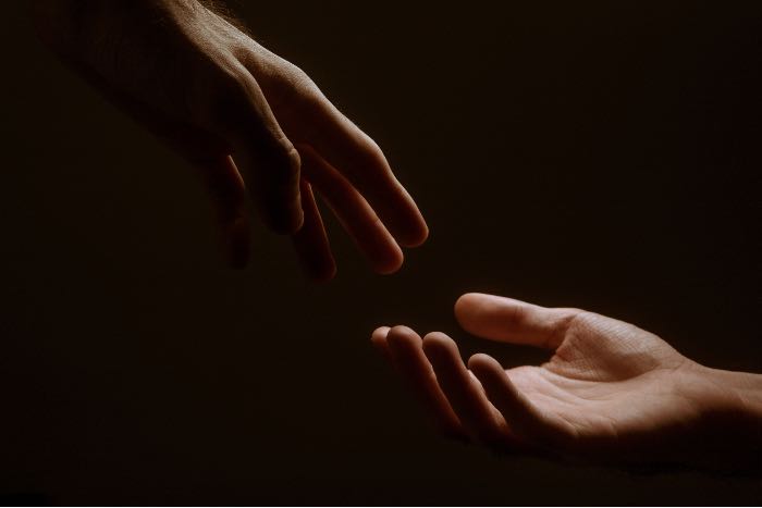 a photo of two hands reaching to each other