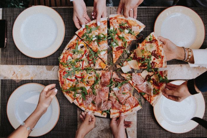 a photo of people taking slices of pizza