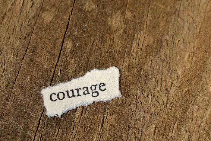 a photo of a wooden table with a scrap of paper with the word "courage" on it.