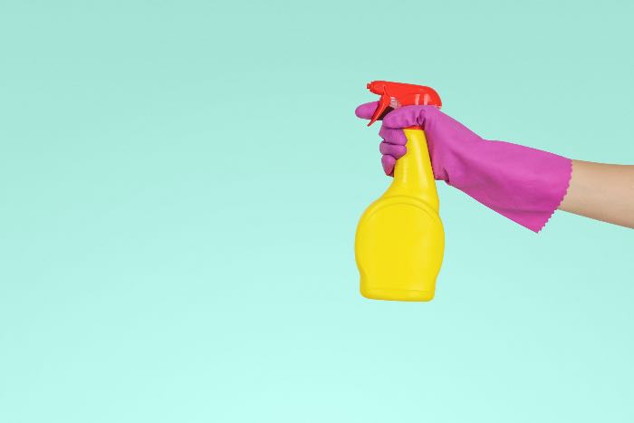 a photo of a spray bottle in a rubber-gloved-hand, ready to clean