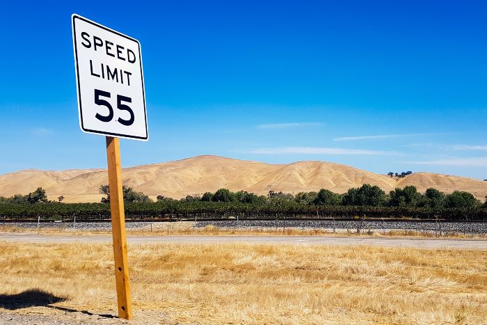 a photo of a sign by a road which says: "Speed Limit 55"