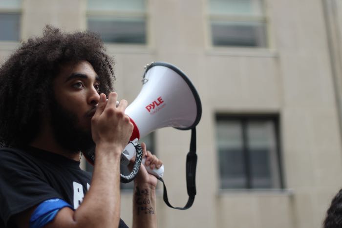 a photo of a person outside with a megaphone - it evokes an image of leading a protest.