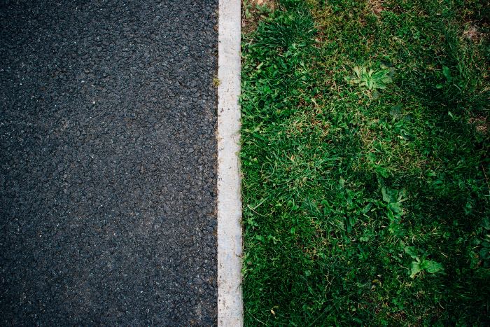 a photo of a white line splitting concrete from grass.