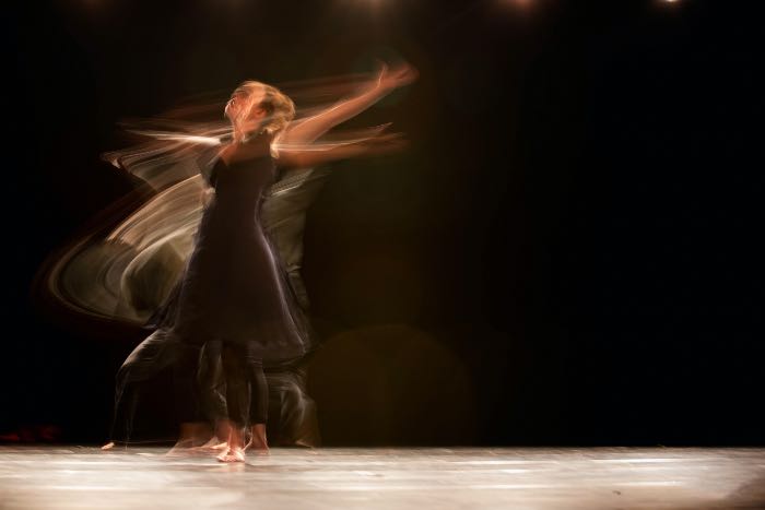 a photo of a person dancing, the slow capture makes the person seem in motion, blurred and mid-movement.