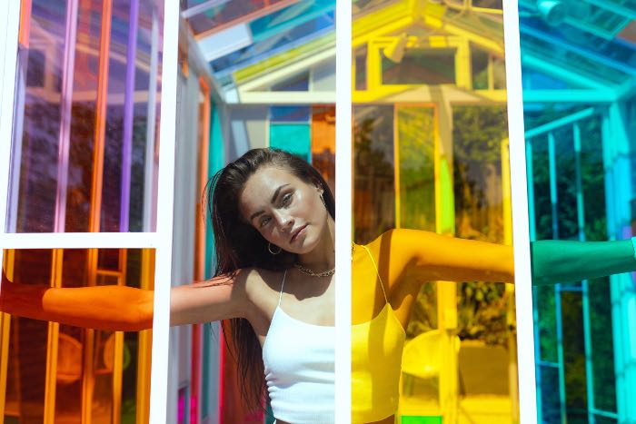 a photo of a person standing behind panes of different colored glass.