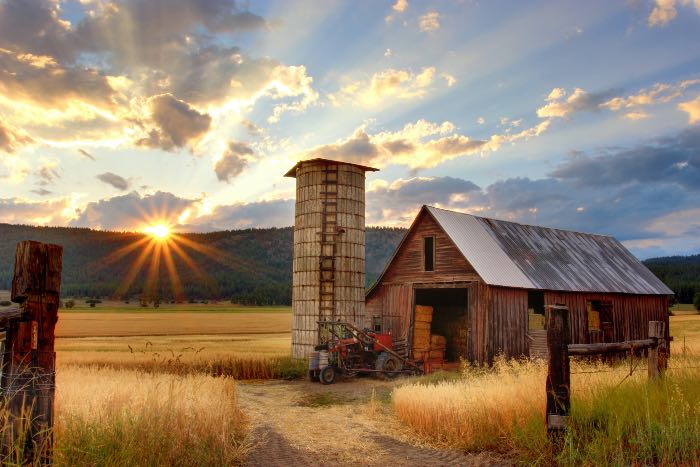a photo of a farm — an old red barn and silo