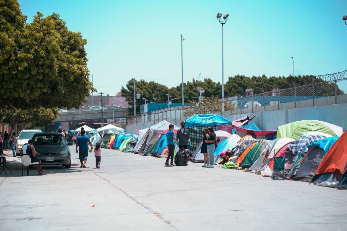 a photo of tents lined up against a fence