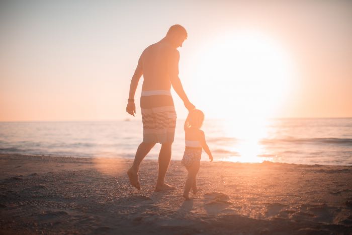 a photo of a father walking on the beach with a child