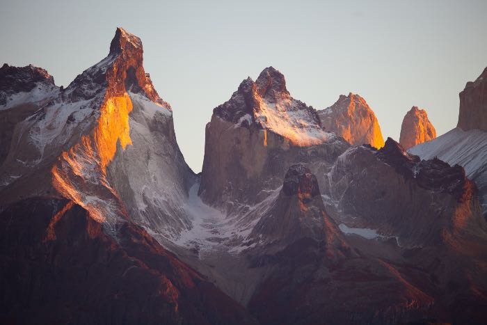 a photo of mountains, with the sun setting on the tops.