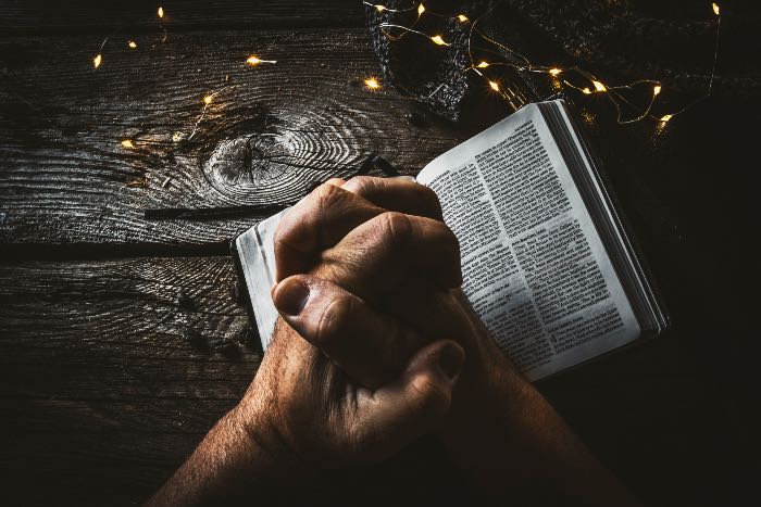 "miracles" a photo of two hands, grasping on a Bible.