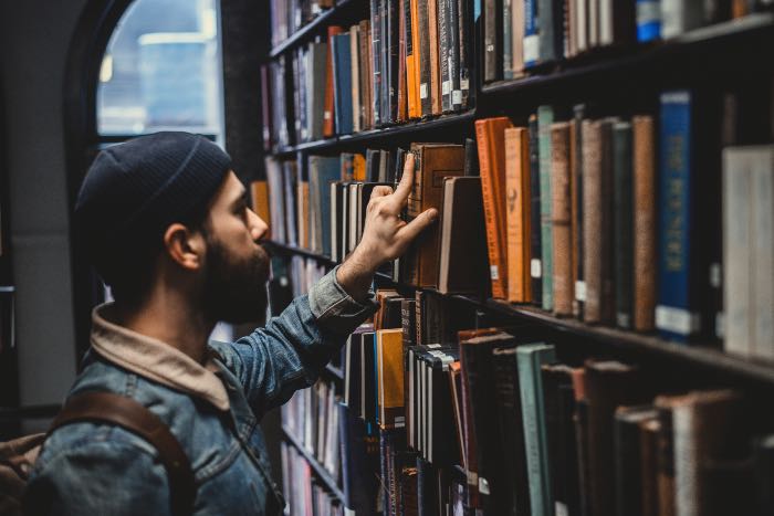 "Why being non-political is a worthy political act" — a photo of a person looking through the book stacks in a library.
