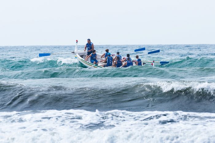 a photo of a boat, people rowing into significant waves