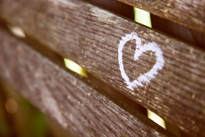 a photo of a park bench, close up, with a heart chalked on it