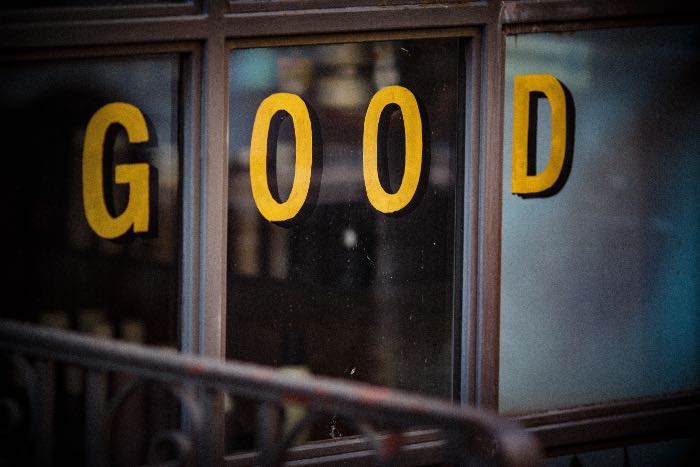 a photo of shop windows with letters painted on them spelling out "GOOD".