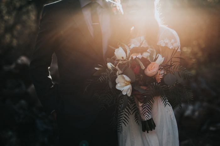 a photo, light distorting the image, of a wedding couple, heads out of the frame, the bouquet near the center.