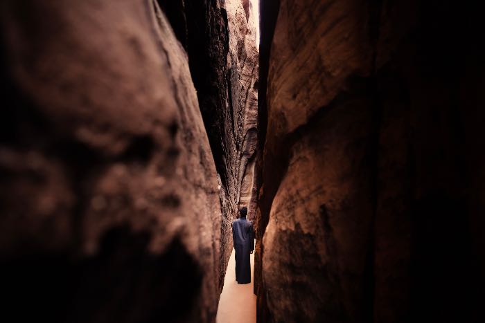 a photo of a person who appears to be walking between two very close walls.