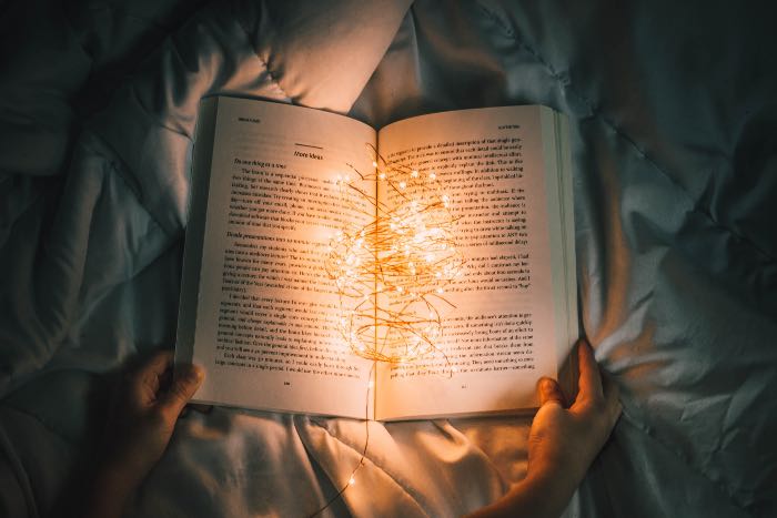a photo of a book, held open, small lights in the center, illuminating the pages.