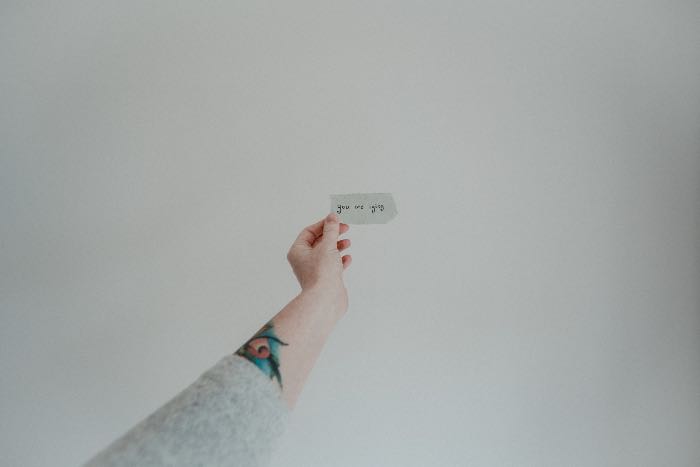 a photo of a hand holding up a small piece of paper, upon which it is written "you are lying"