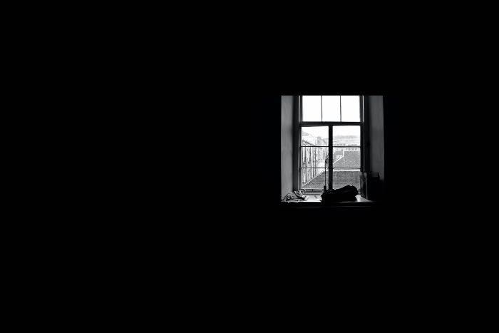 a photo of a very dark room, and a window, open, offering the only light.