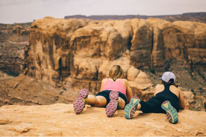 a photo of two women laying on the edge of a canyon