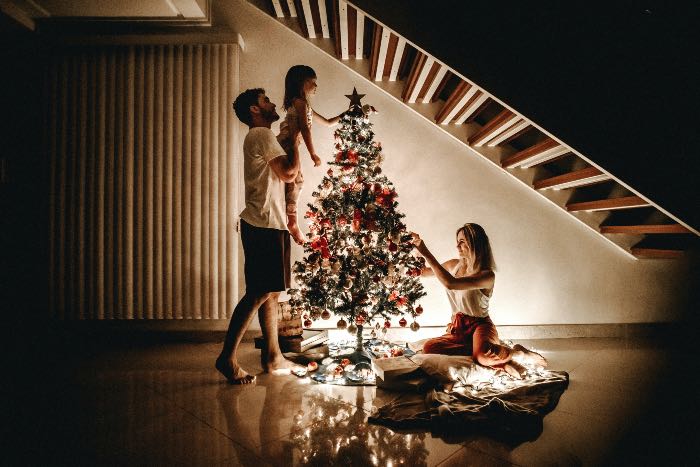 a photo of a family decorating a Christmas tree