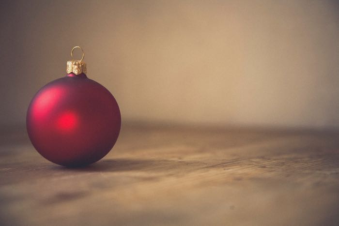 a photo of a red ball ornament resting on a wood table.
