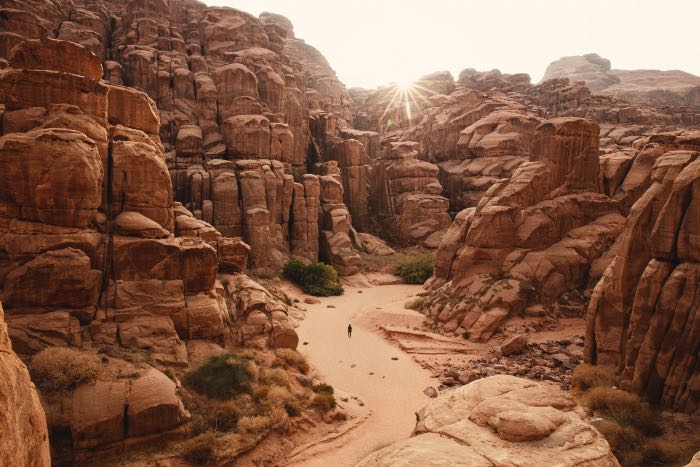 a photo of a person walking through a canyon in the desert.