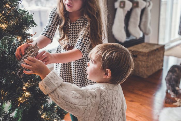 a photo of two children decorating a Christmas tree.