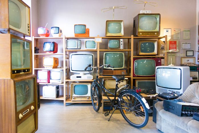 a photo of many old TVs on shelves with a bike in front of them.