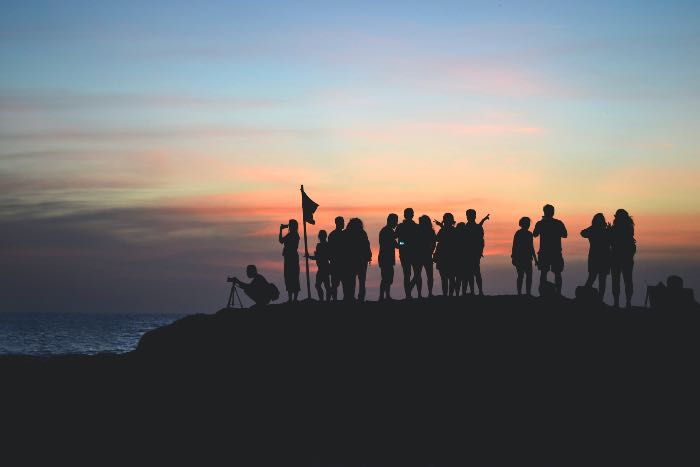 a photo of people gathering at the top of a hill at sunset/sunrise