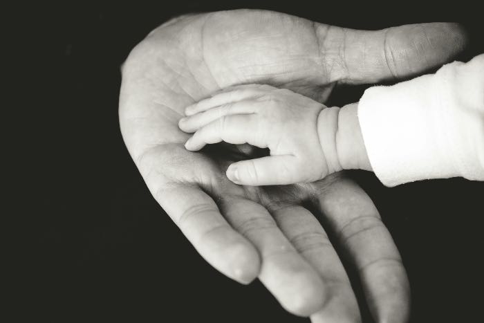 a photo of a baby's hand touching the palm of an adult's