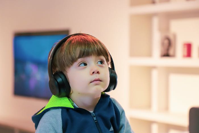 A photo of a child listening to headphones and looking at someone